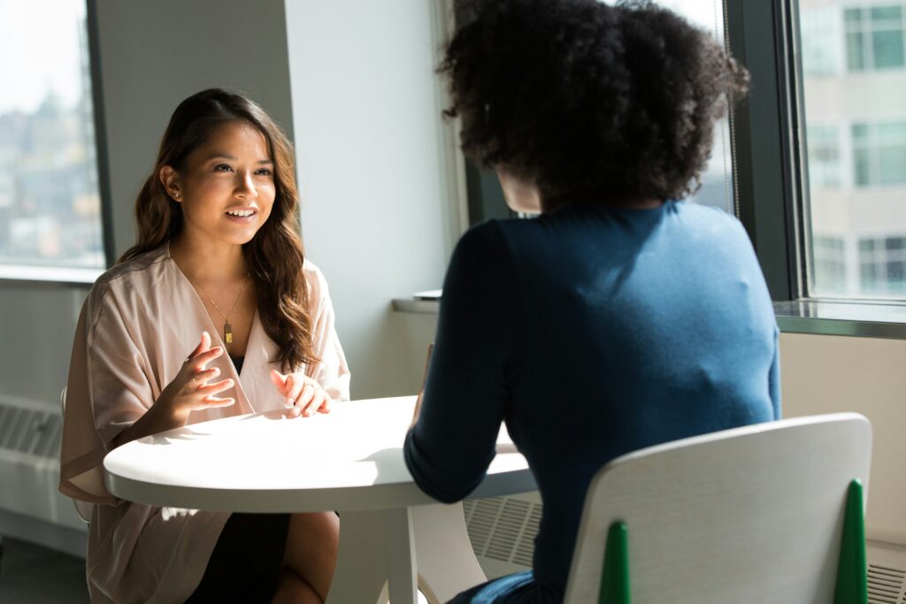Woman speaking with an interviewer across a table.