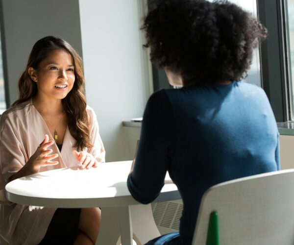 Woman speaking with an interviewer across a table.